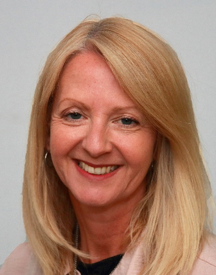Professional headshot of smiling blonde woman in business attire against neutral background