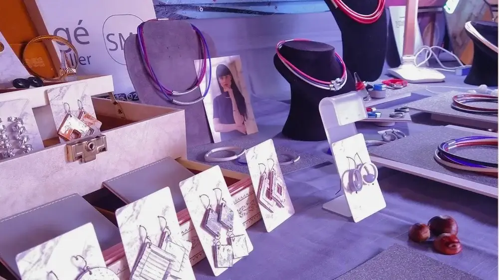 Jewelry display at craft fair with handmade accessories, bracelets, and product cards on white stands