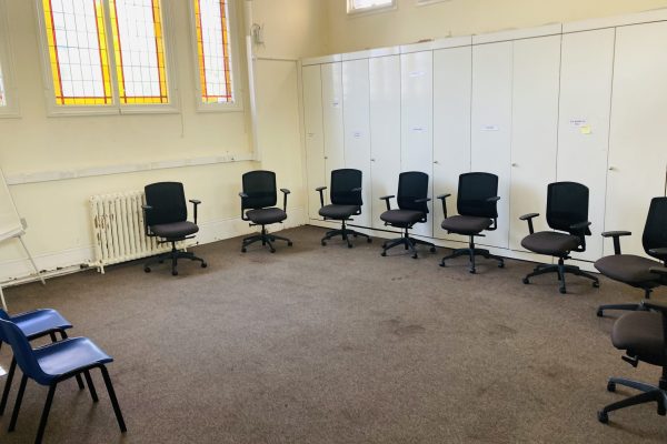 Office chairs arranged in locker room with white storage cabinets and stained glass windows