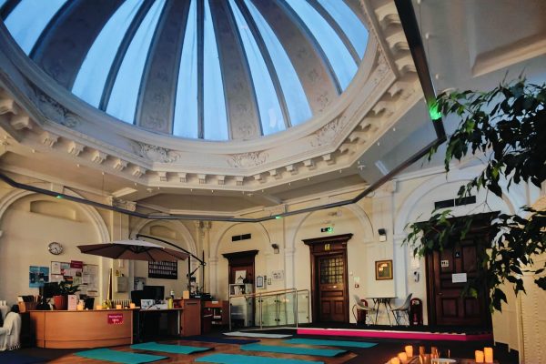 Elegant yoga studio with ornate domed ceiling, turquoise mats arranged on floor, and classical architectural details