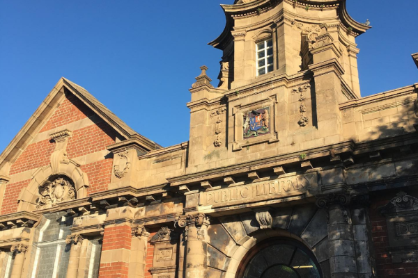Historic brick and stone public library building with ornate tower and dome against clear blue sky