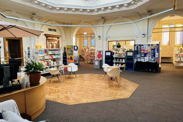 Modern library interior with ornate domed ceiling, computer stations, bookshelves, and contemporary seating area
